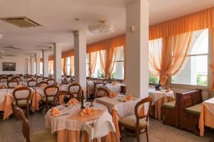 un comedor con mesas, sillas y ventanas en Hotel Mayflower, en Milano Marittima