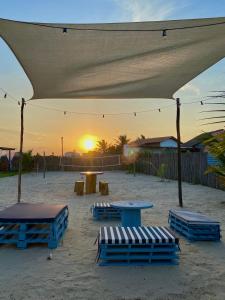 een groep tafels en banken op een strand met zonsondergang bij Luar do Maramar Chalés in Luis Correia