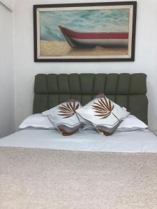 a bed with two pillows and a painting on the wall at Casa para 4 pessoas RJ - Wiffi 500 mb in Rio de Janeiro