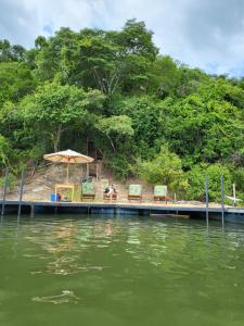zwei Stühle und ein Regenschirm auf einem Steg auf einem Wasserkörper in der Unterkunft EcoAraguaia Jungle Lodge 