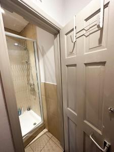 a bathroom with a shower and a glass door at 58 Alloa townhouse in London