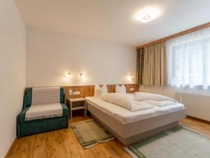 a bedroom with a bed and a chair and a window at Chalet Holdernach in Kappl