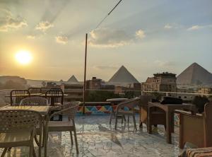 een patio met tafels en stoelen met piramides op de achtergrond bij Nefertiti pyramids view in Caïro