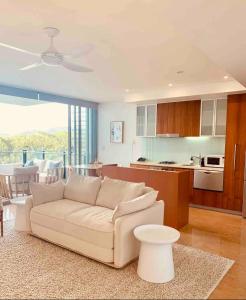 a living room with a white couch and a kitchen at Cotton Beach Resort - Holiday Management in Kingscliff