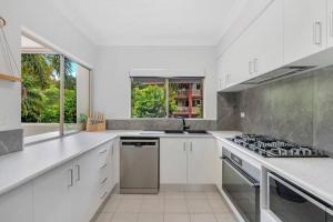 a kitchen with white counters and a stove top oven at 2BR The Lakes Resort Escape, 4 pools 5 min Airport in Cairns North