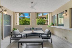 una sala da pranzo con tavolo, sedie e finestre di Cairns 2BR Resort Escape, 4 Pools 5 min to Airport a Cairns North
