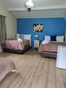 a bedroom with two beds and a blue wall at Hotel Fazenda Santo Antônio in Vassouras