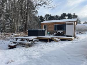 eine Hütte im Schnee mit einem Picknicktisch und einem Kühlschrank in der Unterkunft EcoCottage Private Hot Tub in Union