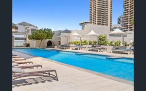 une piscine avec chaises longues et parasols dans l'établissement Level 27 Oceanview Apt In Hilton-Signed Building, à Gold Coast