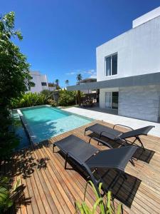 a deck with chairs and a swimming pool next to a house at Casa exclusiva, próximo à Maceió. in Paripueira