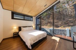 a bedroom with a bed and a large window at Private Pool Villa with filled with stars in Ulsan