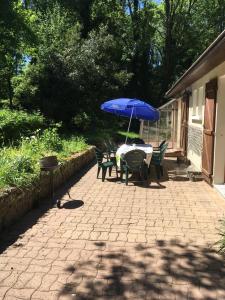 una mesa y sillas con una sombrilla en el patio en Belle Maison proche Disneyland, en Montévrain