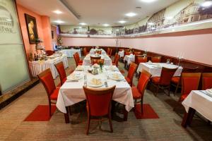 un comedor con mesas blancas y sillas rojas en Hotel Savus, en Slavonski Brod