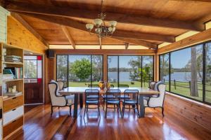 a dining room with a table and chairs and windows at Riverside Ranch - oceanstays in Yamba