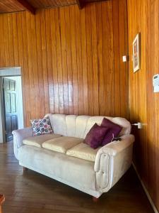 ein weißes Sofa in einem Zimmer mit Holzwänden in der Unterkunft Casa de Campo in Sabalito