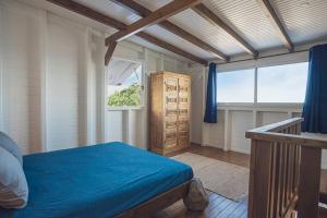 聖安妮的住宿－Cap Sud Bungalow du bourg près de la mer，一间卧室设有蓝色的床和窗户。