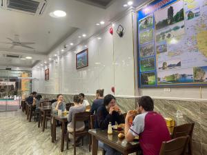 a group of people sitting at tables in a restaurant at CHÂN TRỜI MỚI -NEW HORIZON HOTEL in Cat Ba