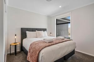 Harakeke Holiday Haven - Taupo في تاوبو: غرفة نوم بيضاء مع سرير كبير ونافذة