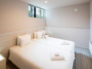 een slaapkamer met een wit bed en een raam bij Olaf House in Niseko