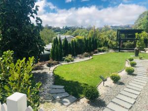 a garden with a lawn and stepping stones at Vista - touch of country and spa in Havelock North