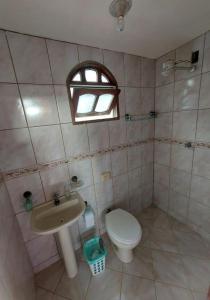 een badkamer met een toilet, een wastafel en een raam bij Uma jóia em frente ao mar! in Piúma