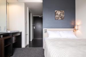 a bedroom with a bed and a desk and a television at Hotel Vista Kumamoto Airport in Ozu