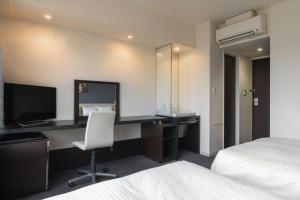 a hotel room with a desk and a television at Hotel Vista Kumamoto Airport in Ozu