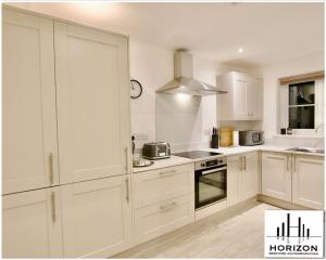 a white kitchen with white cabinets and appliances at Central Durham - Luxury Hideout - Free Parking in Durham