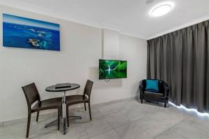 Zimmer mit einem Tisch und Stühlen sowie einem TV in der Unterkunft Deluxe King Studio + top floor sea views in Emu Park