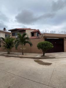 una casa con palmeras frente a una entrada en Casa bonita y cómoda, en Santa Cruz de la Sierra