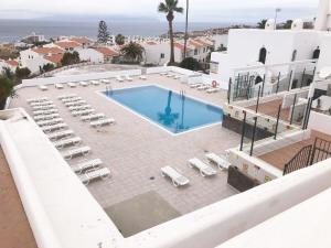 Una vista aérea de una piscina con tumbonas y un complejo turístico. en Apartamento Birgitt en Aloha Garden con vista mar y piscina, en Adeje