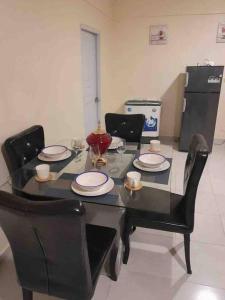 uma mesa de jantar com cadeiras e uma mesa preta com pratos em SDQ Apartamento Marbella I em La Ureña