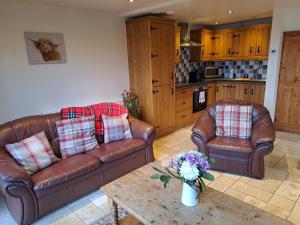 a living room with two leather couches and a coffee table at Orchard Cottage in Bradley in the Moors