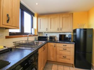 a kitchen with a black refrigerator and wooden cabinets at Marys House in Kilchoan