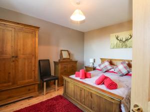 a bedroom with a bed with red pillows and a chair at Marys House in Kilchoan
