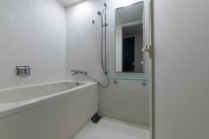 a bathroom with a tub and a sink and a mirror at Hotel Vista Kumamoto Airport in Ozu