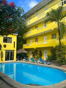 um hotel com piscina em frente a um edifício amarelo em Coco Hotel and Hostel em Sosúa