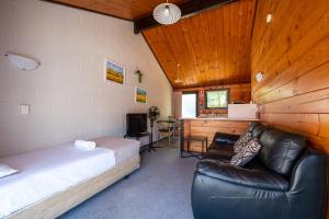 - une chambre avec un lit, un canapé et un bureau dans l'établissement Orewa Motor Lodge, à Orewa