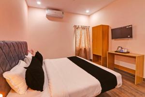 ハイデラバードにあるSuper OYO Flagship RBS Classic Stay Boduppalのベッドとテレビが備わるホテルルームです。