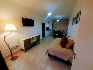 a room with a bed and a desk and a television at A&S Mendoza in Barraquero