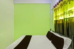 a bedroom with a white bed with a green wall at SPOT ON 7 Day Stay in Chandrapur