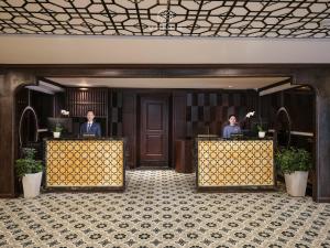 dos personas sentadas en los escritorios de recepción en el vestíbulo del hotel en Venus Halong Cruises en Ha Long