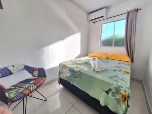 um quarto com uma cama, uma cadeira e uma janela em Mar.4: above-store with balcony near Airport and Stella Maris beach em Salvador