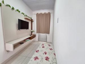 uma sala de estar com uma televisão e um tapete de flores em Mar.4: above-store with balcony near Airport and Stella Maris beach em Salvador