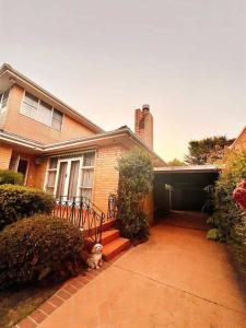 a house with a dog sitting on the front porch at 5 BR & 3 BTH House in Outlook Glen w/ 2 car parks in Glen Waverley