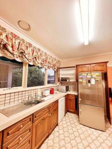 a kitchen with a sink and a refrigerator at 5 BR & 3 BTH House in Outlook Glen w/ 2 car parks in Glen Waverley