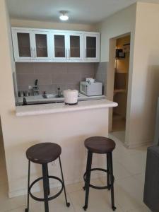 una cocina con dos taburetes sentados en un mostrador en SDQ Apartamento Marbella 1-2, en La Ureña