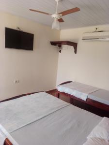 a bedroom with two beds and a ceiling fan at Pousada Estância Mineira in Campo Grande