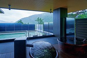a bathroom with a tub and a swimming pool at Hakone Kowakien Hotel in Hakone