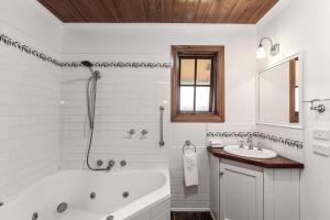 un bagno bianco con vasca e lavandino di Apollo Bay Cottages- Hopetoun a Marengo Altre 19 foto
